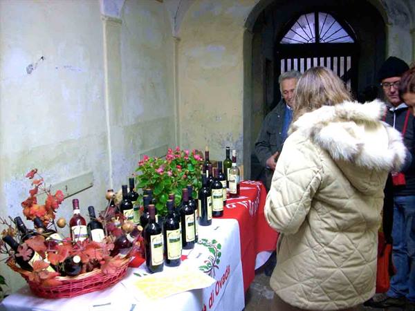 Tourists by wine bottles displayed on a table in an old cellar