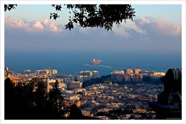 A cargo ship approaches the sea in front of Genoa