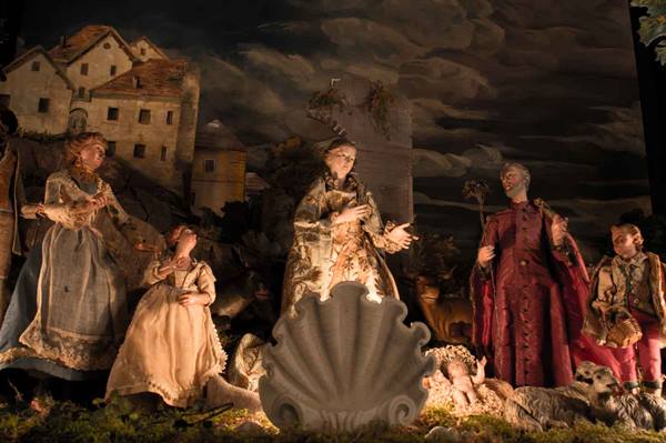 Nativity scene with fabric statues around baby Jesus under painted sky