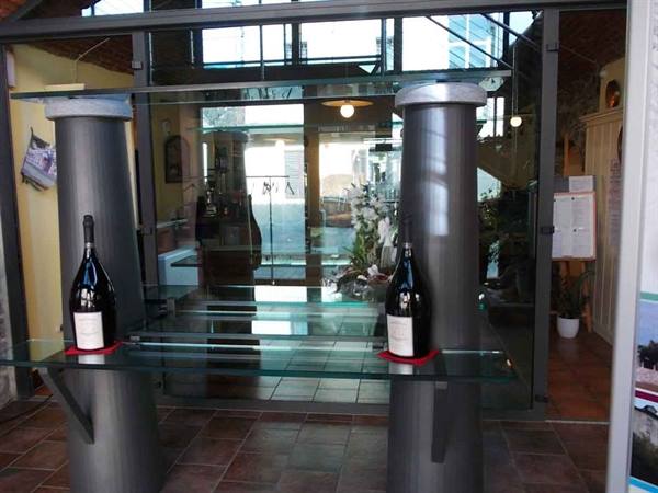 Two large wine bottles on glass shelves between metal columns
