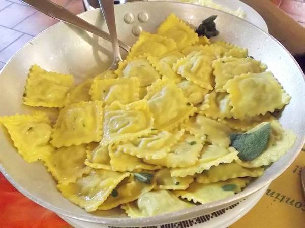 Ravioli with butter and sage served in a pan with cutlery