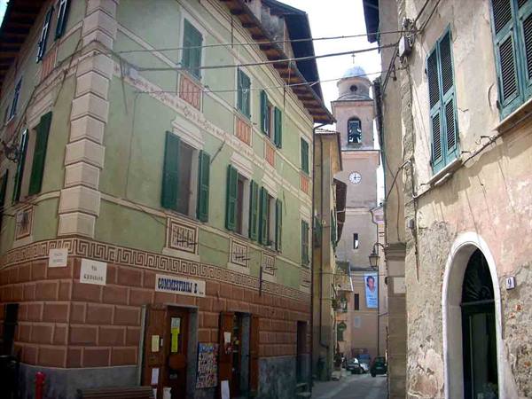 Via Crucis street with hardware store sign, bell tower with clock among shuttered houses