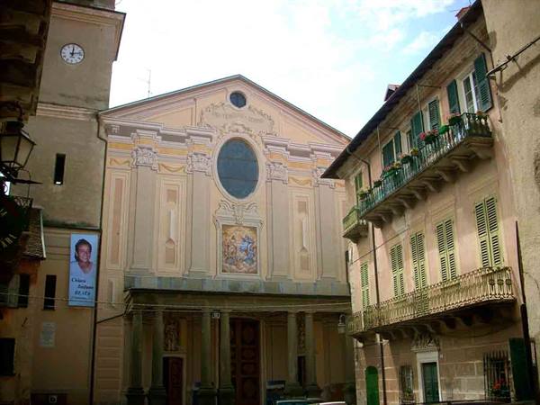 Baroque church with clock bell tower among houses with flowered balconies