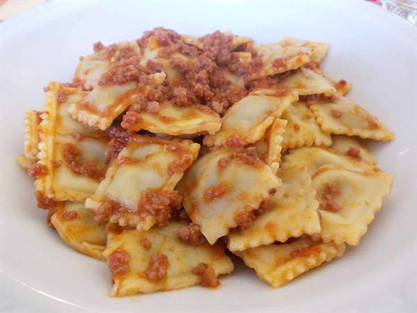 White plate of ravioli with meat sauce, natural daylight