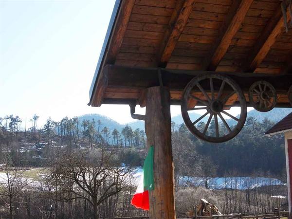 Wooden wagon wheels hanging under timber roof, Italian flag, snowy woods