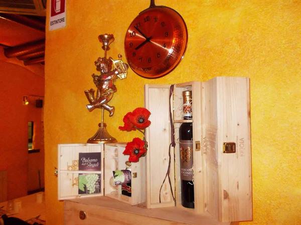Wine bottle in wooden box, copper wall clock and golden cherub on yellow wall