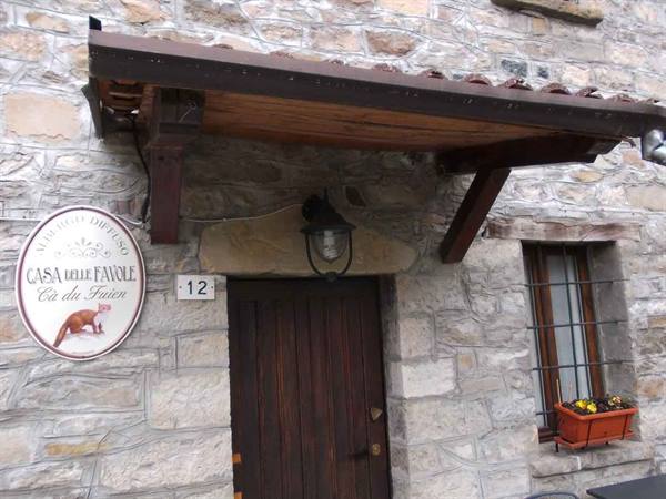 Stone entrance with wooden door, lantern and Casa delle Favole sign