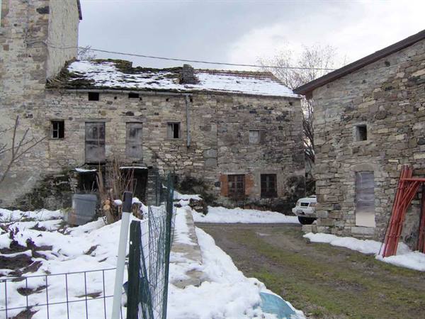 Old stone houses with snow on the roof, small yard and white van