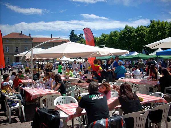 Umbrellas and checkered tablecloth tables in a crowded sunny square
