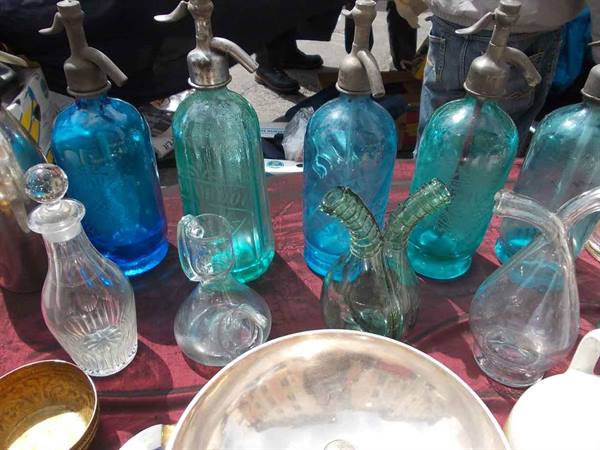 Blue glass siphon bottles and glass decanters at a flea market stall