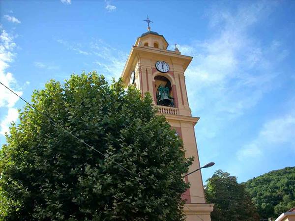 Yellow bell tower with clock and bell above lush green trees