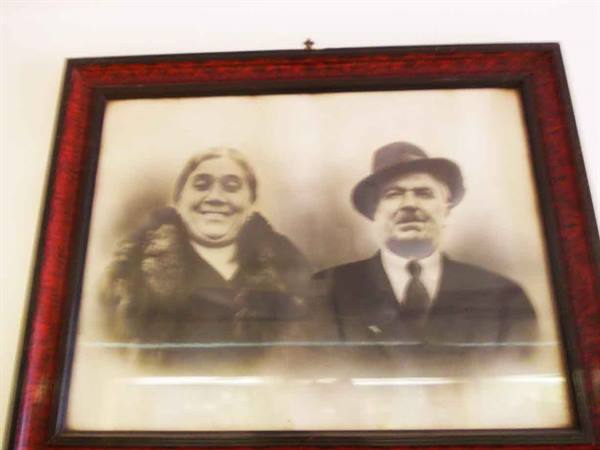 Black and white portrait of elderly couple, man wearing hat, red frame