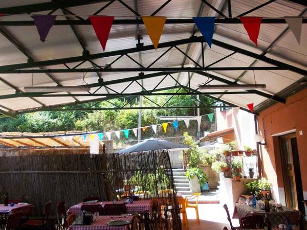 Metal canopy with colorful flags over set tables and a patio umbrella