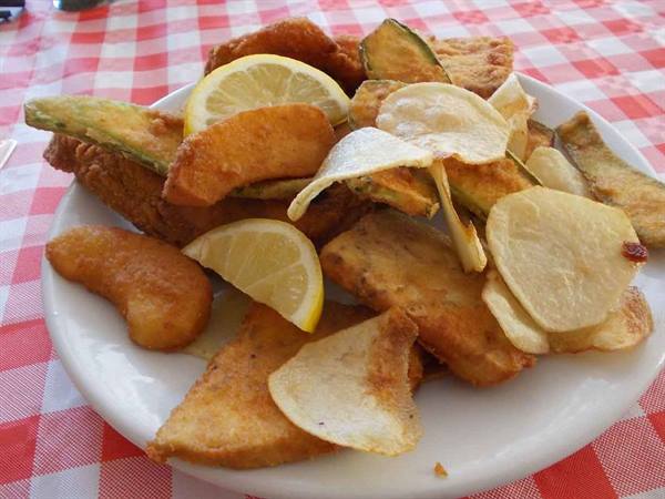 Plate of mixed fried food with zucchini, cod fritters, potato chips and lemon slices