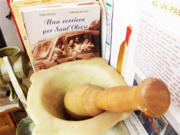 Marble mortar with wooden pestle in front of books and old photographs