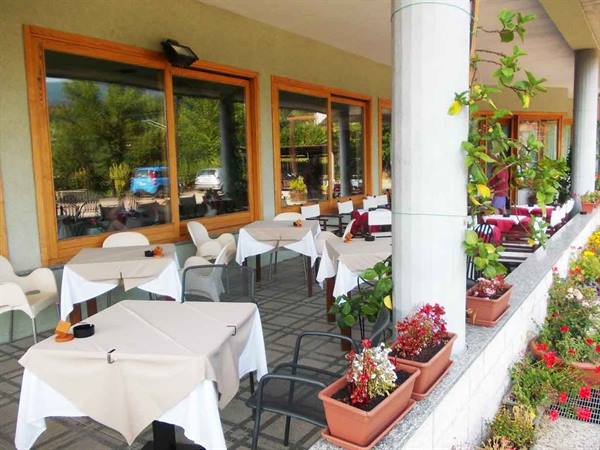 Restaurant terrace with set tables, white tablecloths and pots of red flowers