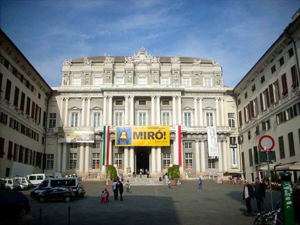 Doge's Palace in Genoa, bright facade with Miro banners, square with pedestrians