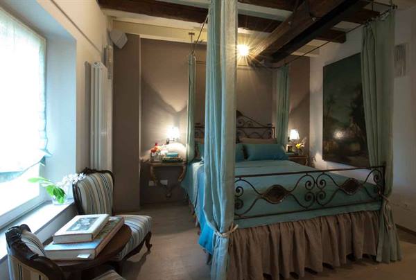 Bedroom with wrought iron canopy bed and exposed wooden beams
