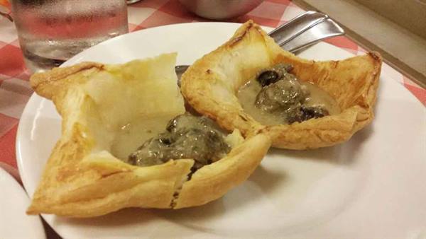 Puff pastry vol-au-vent filled with mushrooms in cream sauce, white plate