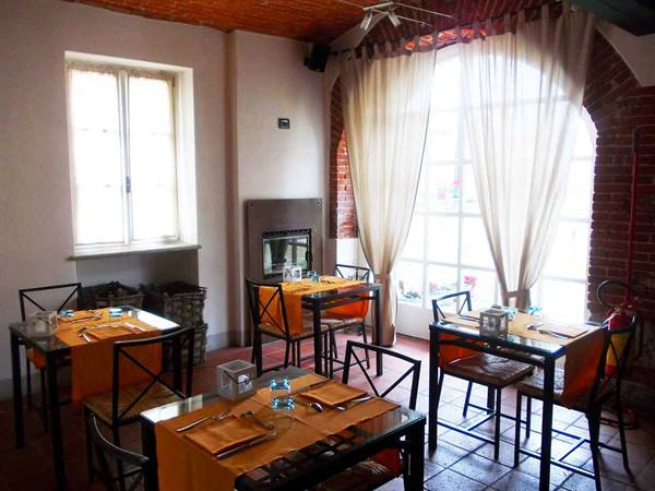 Restaurant dining room with set tables, fireplace, brick ceiling and sheer curtains