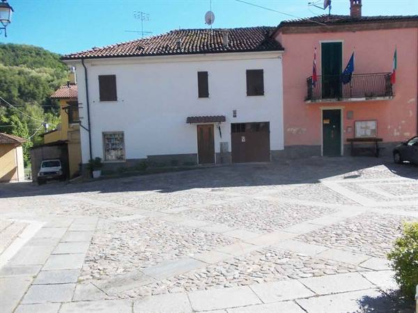 Cobblestone square in front of colorful houses with flags and green hills