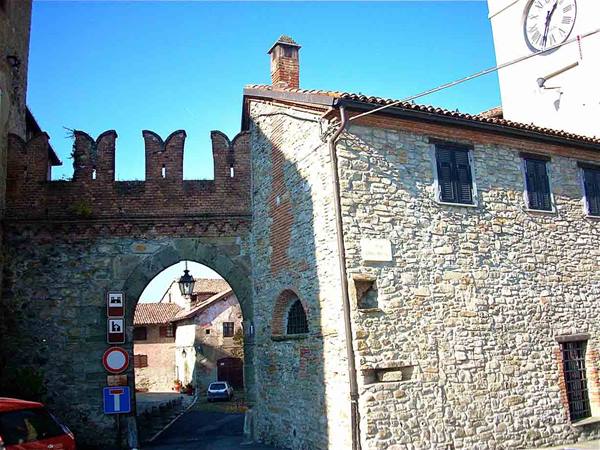 Medieval brick gate with battlements, stone houses and clock tower