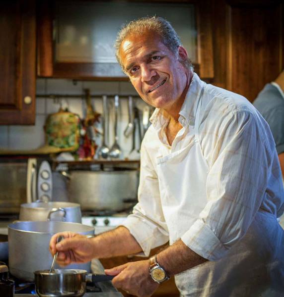 Smiling chef stirring a pot in a wooden kitchen