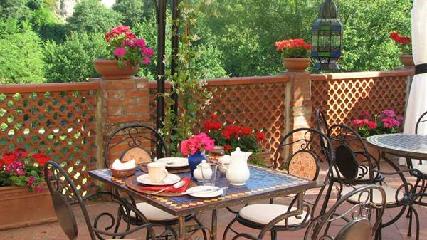 Table with ceramics and flowers on a brick terrace among geraniums