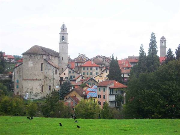 hilltop village with red-roofed houses and two bell towers among trees