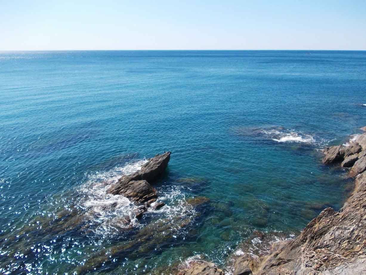 Acqua turchese e onde che si infrangono sugli scogli sotto il sole