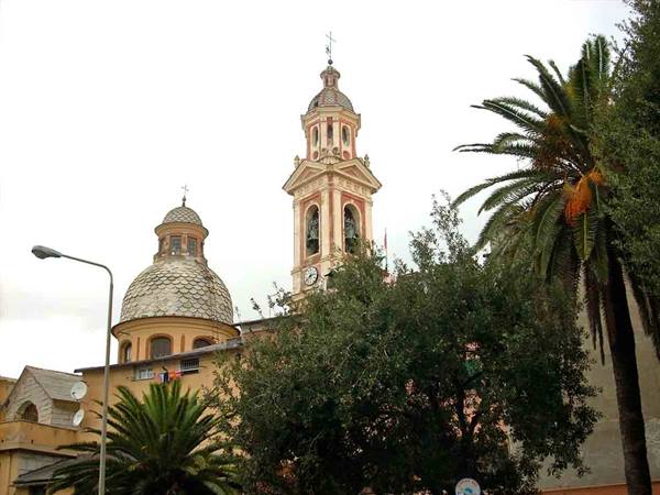 Baroque bell tower with tiled dome among palm trees, grey sky