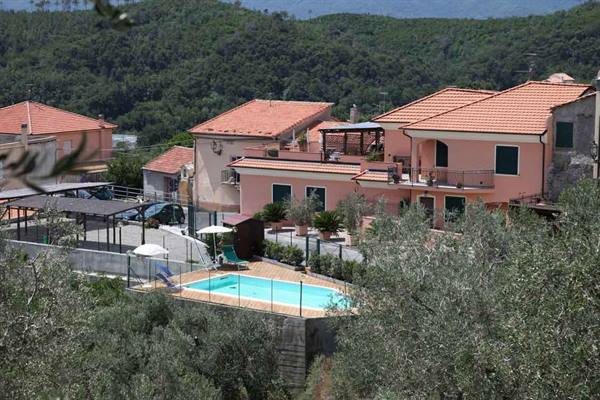 Pink houses with terracotta roofs and swimming pool among olive groves