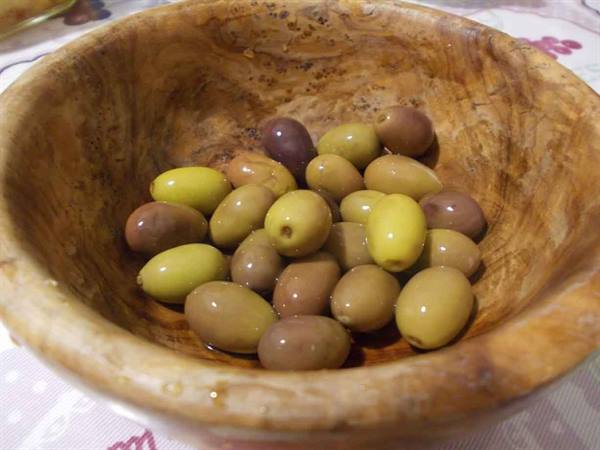 Green and purple olives in a wooden bowl