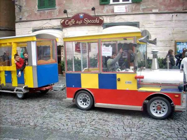 Colorful tourist train on cobblestones in front of Caffè degli Specchi