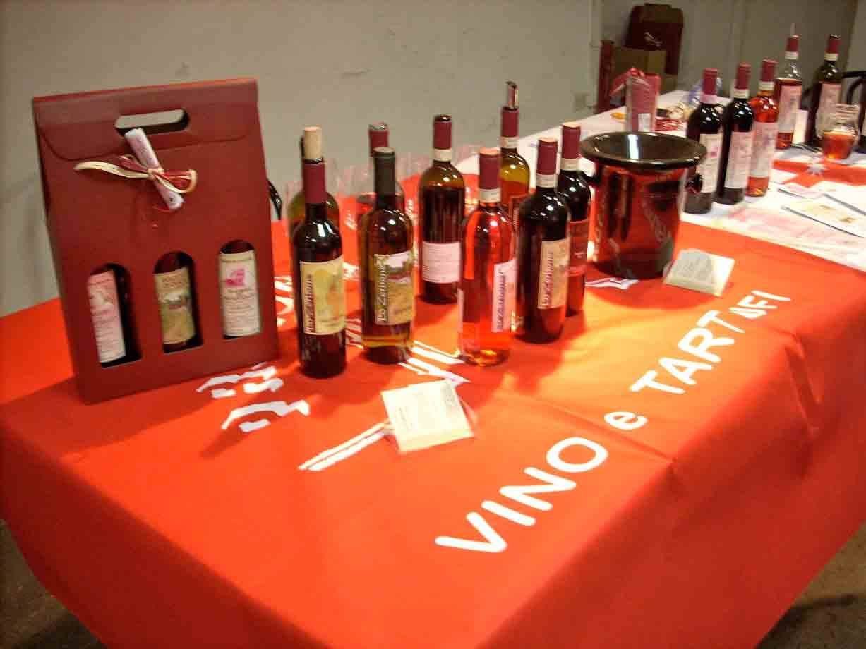 Bottiglie di vino su tavolo con tovaglia arancione scritta vino e tartufi