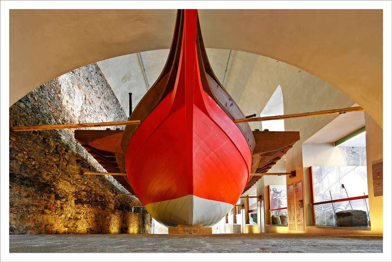 Prua rossa di nave storica in legno, museo navale, volte in pietra
