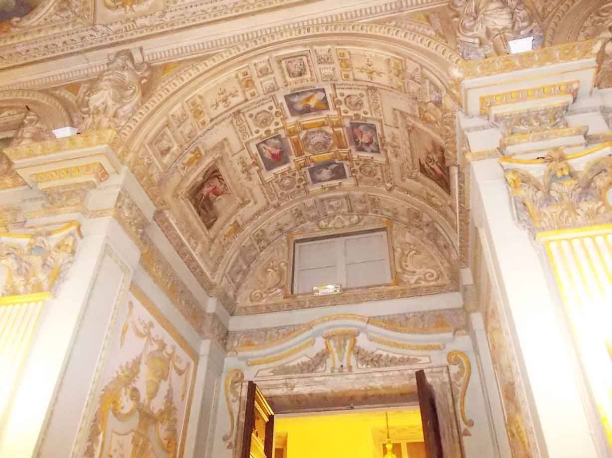 Volta affrescata con pannelli dipinti e stucchi dorati sopra una porta aperta