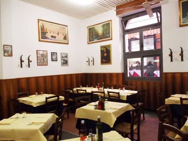 Trattoria dining room with yellow tablecloth tables, paintings and a Mona Lisa copy on the walls