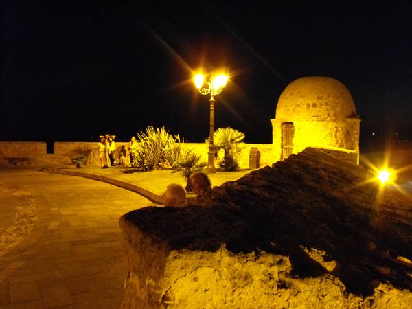 Night stone terrace with illuminated dome, lampposts and people