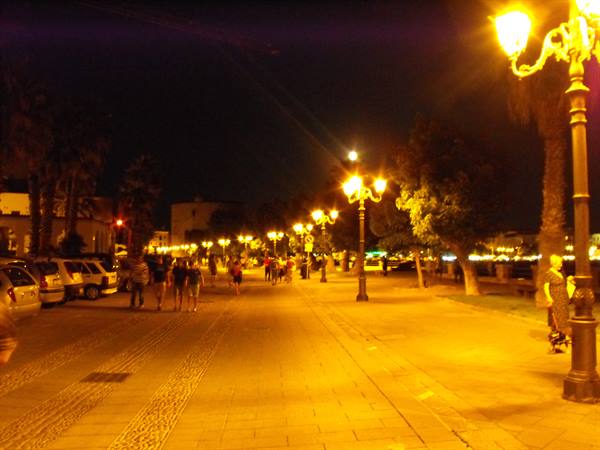Night stroll under glowing lampposts among palm trees and people
