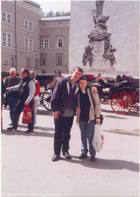 Couple beside the Marian column and horse carriages in Salzburg