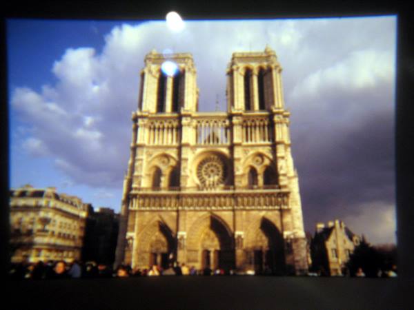 Stone facade of Notre-Dame cathedral in Paris beneath clouds