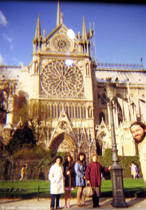 Four women pose in front of Notre-Dame de Paris facade next to a lamppost