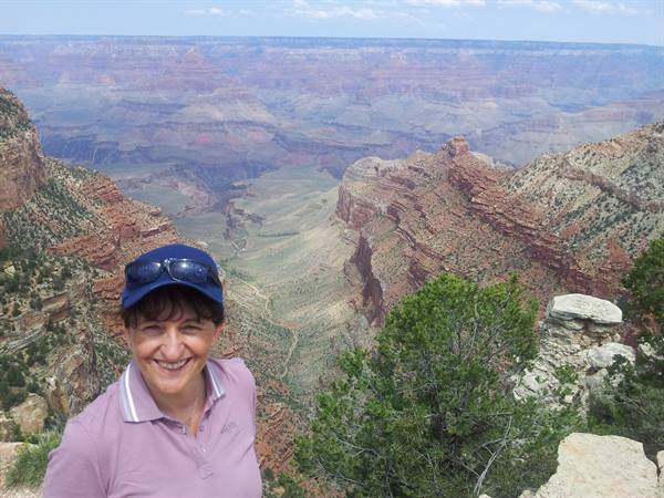 Smiling woman in blue cap and sunglasses before the red rocks of Grand Canyon