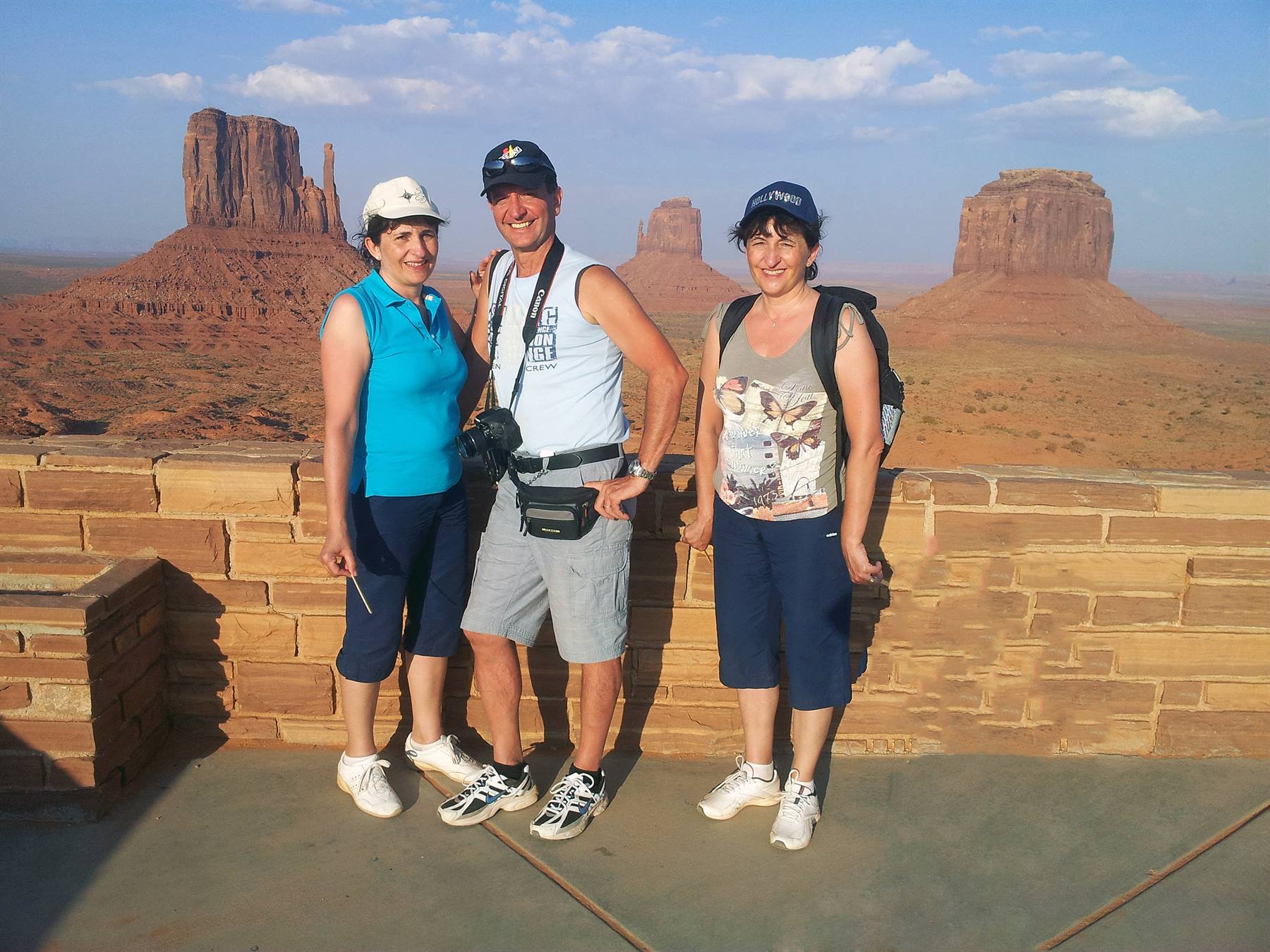 Three tourists pose in front of Monument Valley buttes