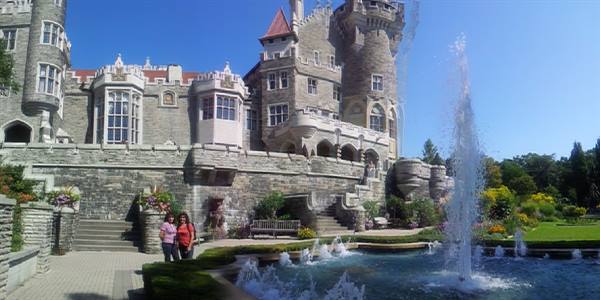 Casa Loma in Toronto, two tourists near the fountain in the sunny garden