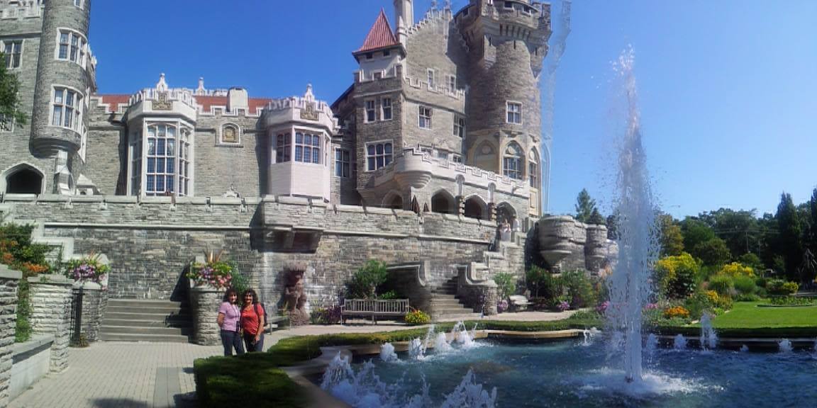 Casa Loma in Toronto, two tourists near the fountain in the sunny garden