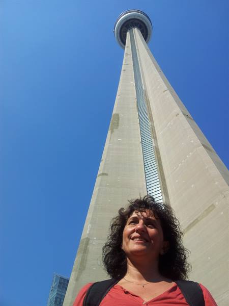 Smiling in front of the CN Tower, Toronto, blue sky, sunlight