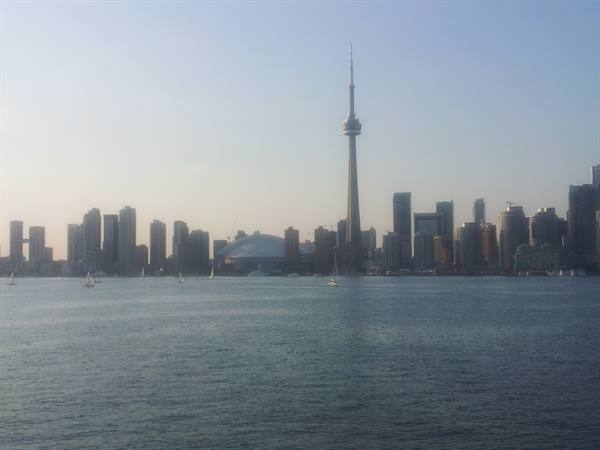 Toronto's CN Tower in haze, skyscrapers and sailboats on the water