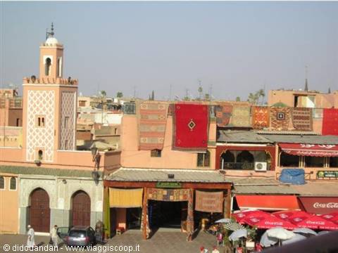 Carpets hanging on pink facades beside a minaret, Marrakech